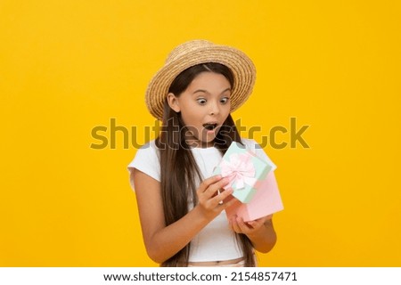amazed teen kid hold gift box on yellow background