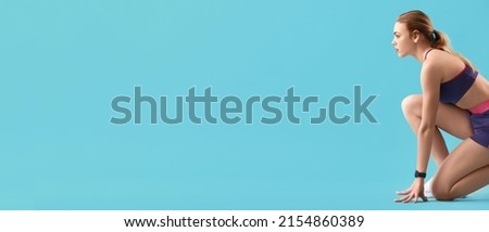 Sporty female runner in crouch start position on light blue background with space for text