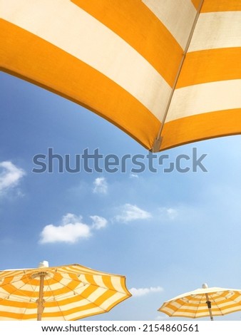 Yellow beach umbrellas on a sunny day. Bright colored umbrellas on the beach. Royalty-Free Stock Photo #2154860561
