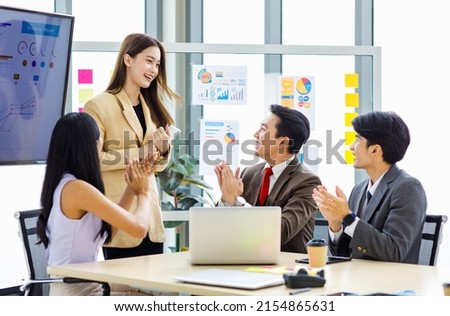 Asian young pretty professional successful businesswoman staff standing greeting say thank you when finishing presentation while male and female colleagues clapping hands together admire compliment.