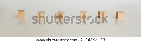 Wooden cubes arranged horizontally on white background with reflection. Conceptual and symbolic image.