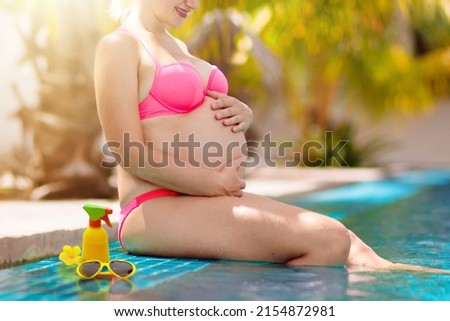 Pregnant woman in swimming pool. UV Sun protection cream for skin. Sunscreen for safe tan. Healthy and active pregnancy.  Young mom on tropical vacation. Swim holiday and water fun for mom and baby. 