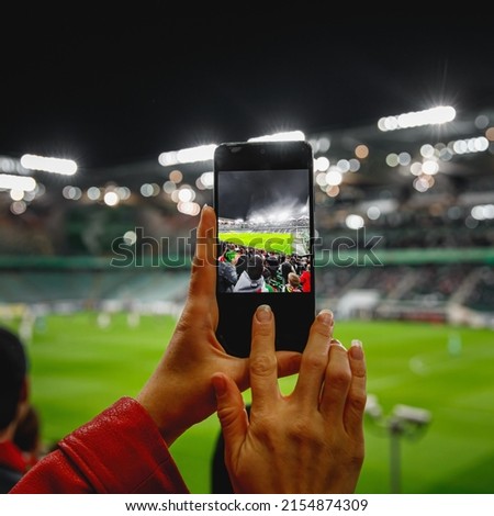 Using a smartphone camera for photographing a football game in the stadium.