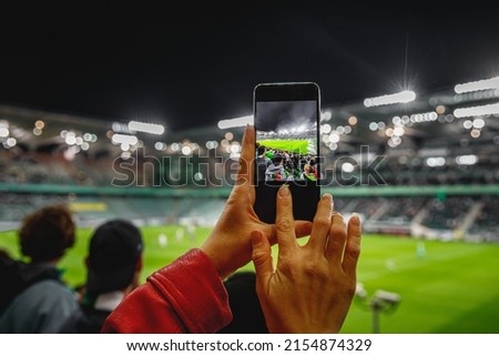 Using a smartphone camera for photographing a football game in the stadium.