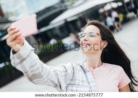 Beautiful fashionable woman looking urban and happy outdoors on a sunny day taking a selfie picture