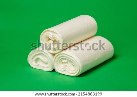 Close up of three rolls of white environmental garbage bags on green background. Bio polyethylene garbage bags are made from secondary raw materials. Eco friendly concept. Banner. Royalty-Free Stock Photo #2154883199