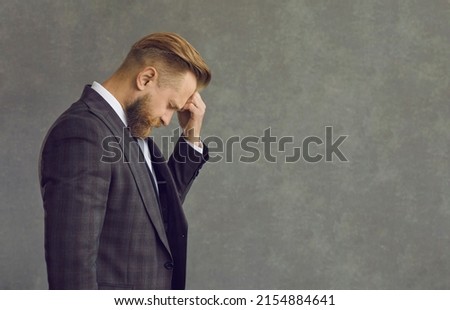 Upset sad depressed businessman in formal suit touching head suffering from headache side view. Studio portrait of people emotion and expression. Frustration and unhealthy anxiety person concept Royalty-Free Stock Photo #2154884641