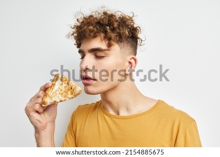handsome guy in a yellow t-shirt eating pizza isolated background