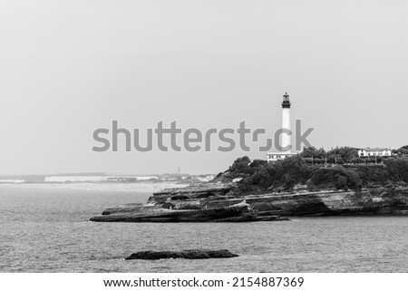 Black and white picture of Biarritz lighthouse on rocks, blurry horizon. Pyrenees-Atlantiques department, French Basque Country