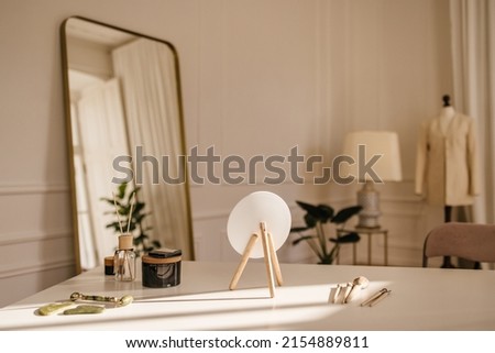White table with facial care tools, table mirror, brushes, quartz roller, scraper in light room. Home spa concept Royalty-Free Stock Photo #2154889811