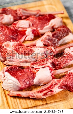 Cut into pieces of raw rack lamb on a cutting board. On a gray background. High quality photo