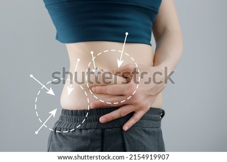 Skinny fat woman figure in fitness clothes touches stomach. Abdominal fat and dieting concept. Massaging marks. Royalty-Free Stock Photo #2154919907