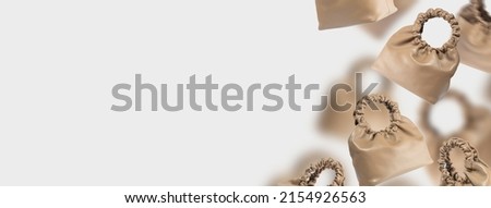 A set of brown bags made of eco-friendly leather. Banner of a floating handbags on a gray background. Composition of fashionable women's accessories. Handmade eco-friendly leather bag. Copy space.