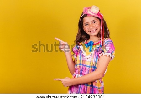 brazilian, caucasian child, festa junina clothes, pointing with finger to negative space, text, advertisement, advertisement. May, June and July festivities, festa junina celebrations