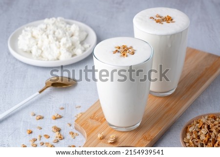 Kefir, buttermilk or yogurt, cottage cheese with granola. Yogurt in glass on light background. Probiotic cold fermented dairy drink. Gut health, fermented products, healthy gut flora concept. Royalty-Free Stock Photo #2154939541