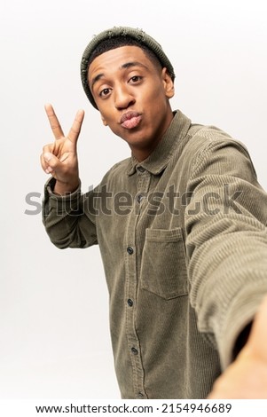 Portrait of young adult handsome man taking selfie, looking at camera POV and gesturing hand, point of view of photo. Indoor studio shot isolated on white background