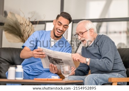 Old man and his caretaker laughing at a news item Royalty-Free Stock Photo #2154952895