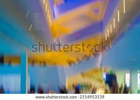 Abstract blurred shopping mall indoor, modern building, stairs and platforms, silhouettes of people, bright background