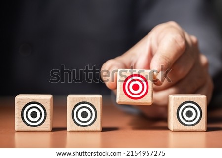 Closeup man pick one of wood blocks in a row with a different target symbol, choose or narrow the target to reach the customers Royalty-Free Stock Photo #2154957275