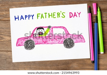 A child's drawing on a wooden table. Dad is driving a car. A postcard for the Father's Day holiday