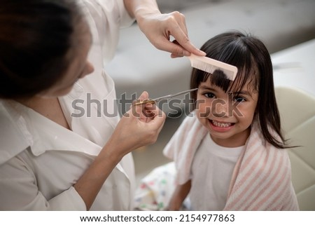 Asian Mother cutting hair to her daughter in living room at home while stay at home safe from Covid-19 Coronavirus during lockdown. Self-quarantine and social distancing concept. Royalty-Free Stock Photo #2154977863