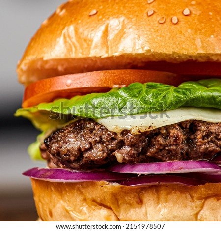 A vertical, close-up shot of a juicy hamburger isolated on a blurred background