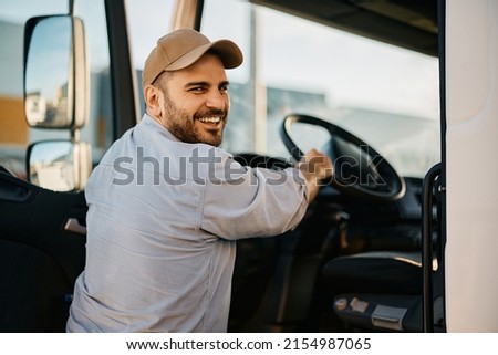 Happy professional driver entering in truck cabin and looking at camera. Royalty-Free Stock Photo #2154987065