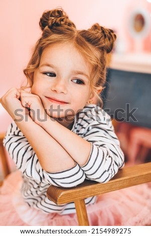 Stylish little girl in a beauty salon for children where she made a beautiful hairstyle