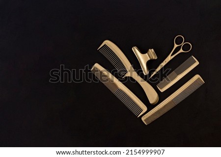 Hairdressing tools in black and gold on concrete background. Hair salon accessories, combs, scissors and hair clips and with copy space. Template for business cards