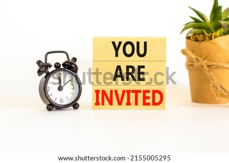 You are invited symbol. Concept words You are invited on wooden blocks. Black alarm clock. Beautiful white table white background. Business and you are invited concept. Copy space.
