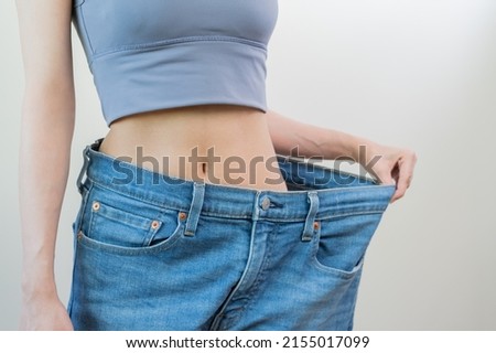 Shape slender, thin waist, attractive slim asian young woman, hand show shape her weight loss, wearing in big, large or oversize jeans, excess lose by diet and exercise. People body fit healthy. Royalty-Free Stock Photo #2155017099