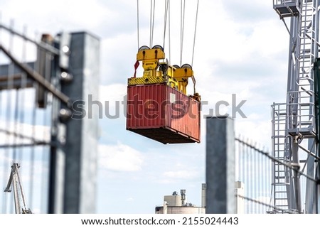 A container gantry crane on a rail loads the container into a barge standing on the banks of the river Rhine in Germany. Royalty-Free Stock Photo #2155024443