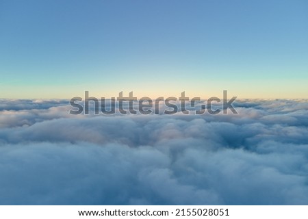 Aerial view from airplane window at high altitude of dense puffy cumulus clouds flying in evening Royalty-Free Stock Photo #2155028051
