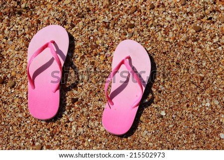 Children's pink flip flops on the sand