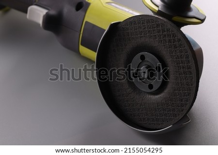 Electrical saw, grinder with nozzle on grey surface, detailed picture of powerful circular saw tool