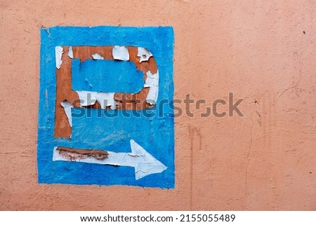 Deteriorated parking sign on a red clay wall