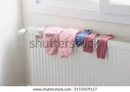 Colorful woolen socks drying on a radiator heater in home. Winter time, cold weather lifestyle. Royalty-Free Stock Photo #2155059127