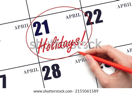 21st day of April.  Hand drawing a red circle and writing the text Holidays on the calendar date 21 April. Important date. Spring month, day of the year concept.