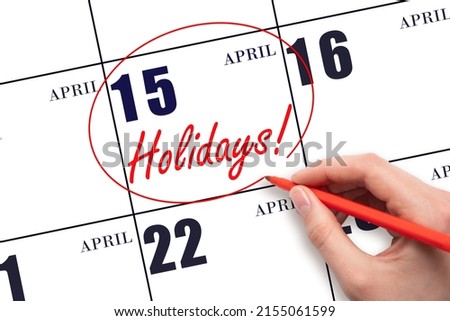 15th day of April.  Hand drawing a red circle and writing the text Holidays on the calendar date 15 April. Important date. Spring month, day of the year concept.