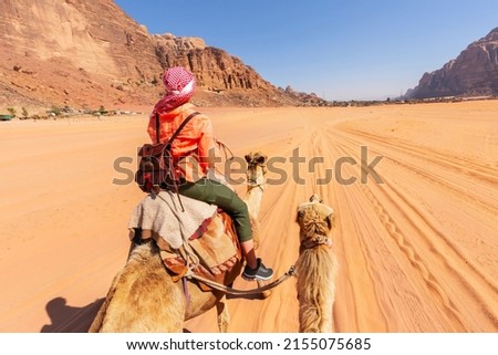 beautiful young woman tourist in white dress riding on camel in wadi rum desert, Jordan Royalty-Free Stock Photo #2155075685