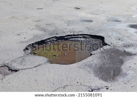The asphalt pavement on the road was destroyed. Poor condition of roads requiring repair. View from above. Construction and repair of roads. A hole in the asphalt Royalty-Free Stock Photo #2155081091
