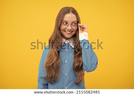 Happy teenage school girl fix eyeglasses smiling yellow background, eyewear