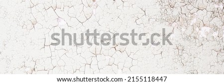 Peeling paint on the wall. Panorama of a concrete wall with old cracked flaking paint. Weathered rough painted surface with patterns of cracks and peeling. Panoramic texture for background and design. Royalty-Free Stock Photo #2155118447