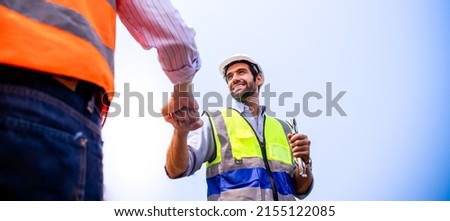 
Handsome European engineers greet each other with fist bumps. Middle Eastern workers smiling with confidence, happy at work, professional, wearing PPE,hard hat,reflective,vest.New normal professional Royalty-Free Stock Photo #2155122085