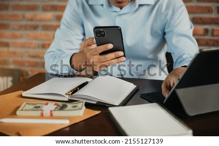 Business man working at office with smartphone and tablet on his desk, financial adviser analyzing data.