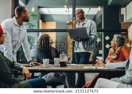 Diverse business professionals having a discussion during a meeting in a modern office. Team of multicultural businesspeople sharing creative ideas in an inclusive workplace. Royalty-Free Stock Photo #2155127675