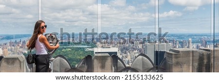 USA travel tourist in New York City vacation- woman looking at view of skyline with binoculars from skyscraper. Girl traveling summer holidays United States road trip