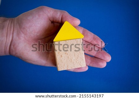 Cubes in the form of a house in hand. Saving at home. Acquisition of housing abroad. Under protection. The housing deal went through.