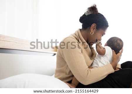 African young mother hugging and playing with her adorable baby on bed