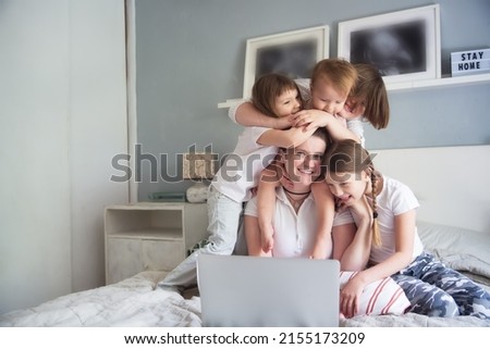 Mom and 4 children are looking at a laptop, watching a movie together. Mom freelancer working at home with children, motherhood and work, watching cartoons together